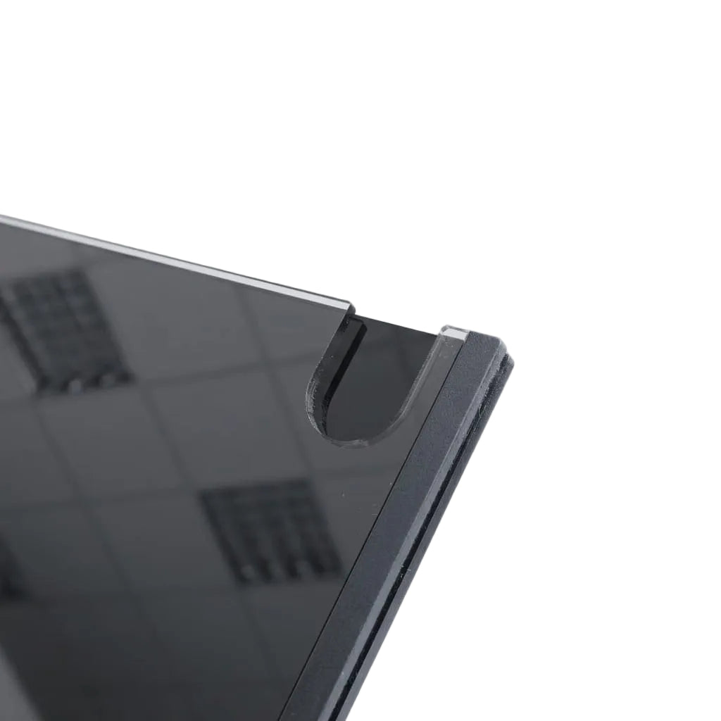 Close-up of a dark gray or black tablet or monitor corner with a glossy screen and a small transparent protective film along the edge, set against a light gray background.