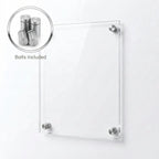 A clear rectangular acrylic or glass wall plaque mounted with four silver metal studs on a plain white wall.