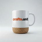 A white ceramic coffee mug with a cork base and the 'crafts.unit' logo printed on the side, set against a clean light gray background.