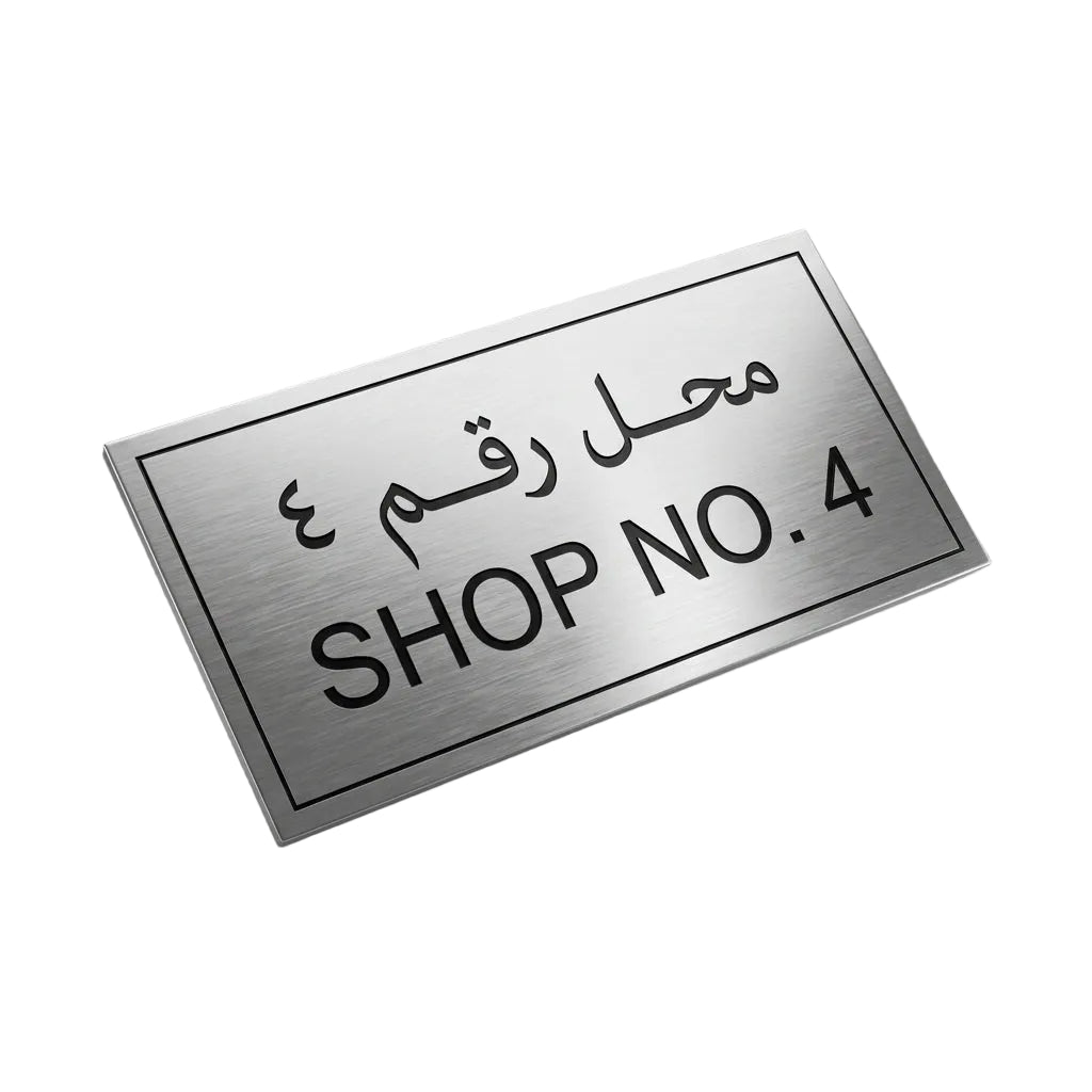 A rectangular brushed-metal sign with black Arabic text above the English text 'SHOP NO. 4', shown floating at an angle on a white background.